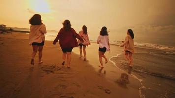 un grupo de asiático adolescentes en camisas jugando en el playa con su amigos felizmente video