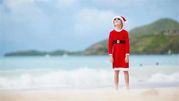 petite fille adorable au chapeau de noël sur la plage blanche pendant les vacances de noël video