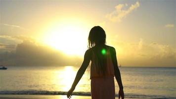 adorabile contento poco ragazza su bianca spiaggia a tramonto. video