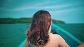 An Asian woman with blonde hair is enjoying the sea breeze while boarding a fishing boat while on vacation and is very relaxed video