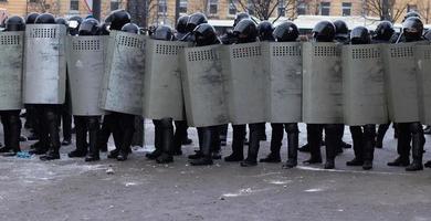 Riot police force with shields in row on city street photo