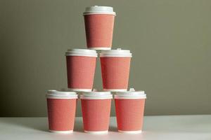 Pyramid of coffee cups with gray background. Cup of coffee. Takeaway or takeout business. photo