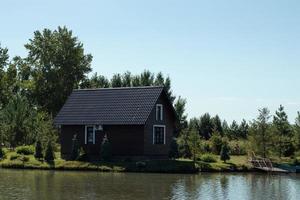 pequeño de madera casa por el lago en el bosque foto