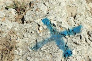 Blue cross as a mark on the rock surface, treasure hunt concept photo