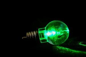 Green lightbulb on black background photo