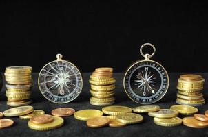 Compass and coins on black background photo