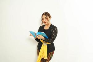 Balinese woman holds a book while adorned in traditional attire, showcasing the  blend of culture and education. photo