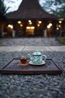 A teapot filled with hot tea, along with a glass, is ready to be served and enjoyed in the  Afternoon. photo