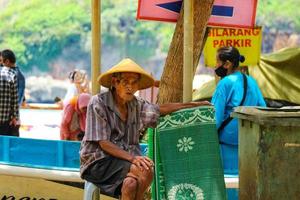 Yogyakarta, Indonesia in November 2022. Photo of a grandfather or old man renting mats at Baron Beach.