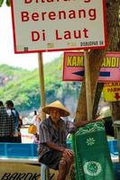 Yogyakarta, Indonesia in November 2022. Photo of a grandfather or old man renting mats at Baron Beach.