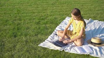 Little girl outdoors in the park with computer video