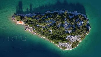 vista aérea de drones de una pequeña isla en la bahía de mali ston ubicada en la península de peljesac. granjas de ostras en el agua de mar turquesa. mezcla única de agua dulce y agua de mar. video