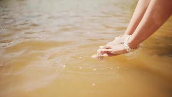 A beautiful Asian woman play with the water and washes her hand in the lake while wearing a black dress and golden crown video