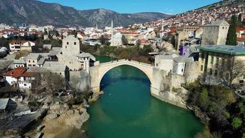 luftdrohnenansicht der alten brücke in der stadt mostar in bosnien und herzegowina an einem sonnigen tag. blaue türkisfarbene farben des flusses neretva. Unesco-Weltkulturerbe. Leute, die über die Brücke gehen. video