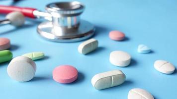 Colorful pills and stethoscope on blue background .