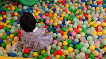 Top view of child girl playing with many colorful plastic ball video