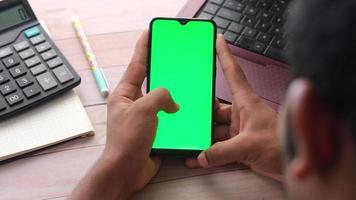 alto ángulo ver de hombre utilizando móvil inteligente teléfono con verde pantalla . video