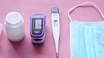 Pulse oximeter, face mask and medical pill container on table . video