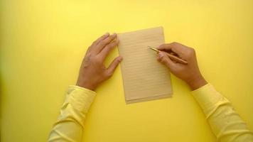 Man hand writing on a paper on yellow background . video