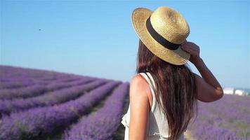 Woman in lavender flowers field at sunset in white dress and hat video