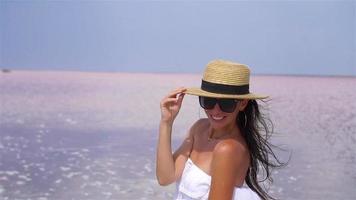 Woman in hat walk on a pink salt lake on a sunny summer day. video