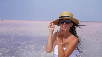 vrouw in hoed wandelen Aan een roze zout meer Aan een zonnig zomer dag. video