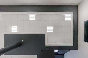 cassette stretched or suspended ceiling with square halogen spots lamps and drywall construction in empty room in house or office with column. Looking up view photo