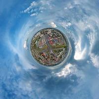 tiny planet in sky with clouds overlooking old town, urban development, historic buildings and crossroads. Transformation of spherical 360 panorama in abstract aerial view. photo