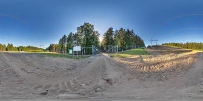 full seamless hdri 360 panorama on gravel road in front of fence of forbidden zone, border or reserve in pinery forest in equirectangular spherical projection near power lines and high voltage poles photo