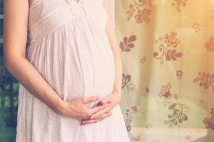 close up hand pregnant woman holding tummy with vintage toned photo