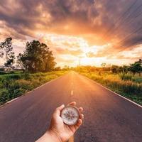 Hand man holding compass on road with sky sunset. photo