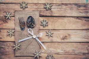 christmas table place setting and silverware, snowflakes on wooden background with space. photo