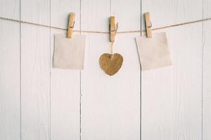 Two blank old paper and brown heart hanging. On white wooden background with vintage style. photo