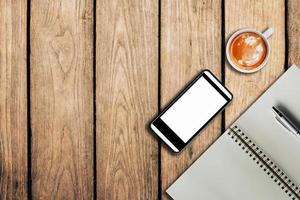 smartphone coffee cup and notebook on wooden background with space. photo