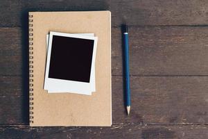 notebook and pencil with frame photo on wood table background with space