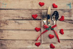 mesa conjunto para celebracion San Valentín día. de madera mesa sitio ajuste y cubiertos con rojo corazón para enamorado día. foto