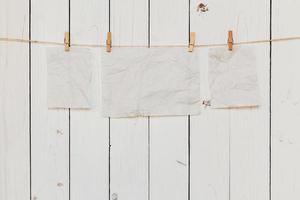 Blank old paper hanging on white wood background with space for text. photo