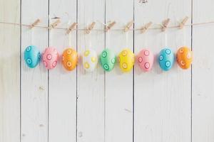 Colorful easter eggs hanging on rustic wooden white background with space. easter eggs background. photo