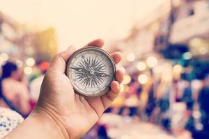 Hand holding compass and Blurred crowd of people walking through a city street. vintage toned photo. photo