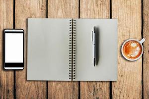 smartphone coffee cup and notebook on wooden background with space. photo