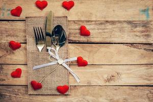 Table set for celebration Valentine's Day. Wooden table place setting and silverware with red heart for Valentine day. photo