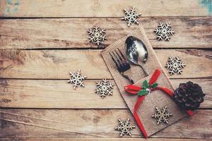 christmas table place setting and silverware, snowflakes, pine cones on wooden background with space. photo