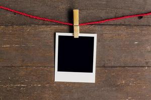 Blank photo frame with clothesline hanging on wood background.