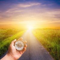 mano hombre participación Brújula navegador en la carretera camino con luz de sol. foto