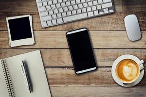 Office table with coffee cup, computer, phone, notebook and pen. View from above with copy space photo