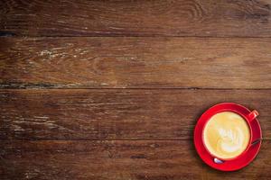 red coffee cup on old wood background with space. photo