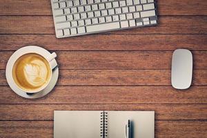 Office table with notepad, computer and coffee cup and computer mouse. View from above with copy space photo