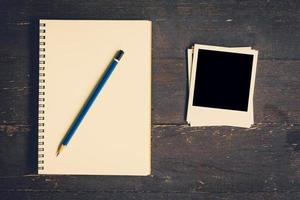 notebook and pencil with frame photo on wood table background with space