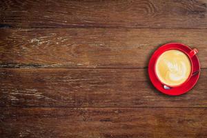 red coffee cup on old wood background with space. photo