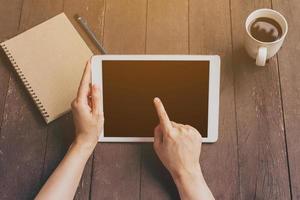 Hand woman using tablet on table in garden at coffee shop with vintage toned. photo